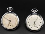 two clocks sitting side by side on a black surface