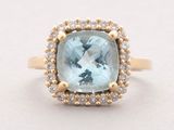 a close up of a ring with a blue topaz stone surrounded by diamonds