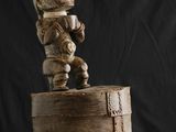 une image représentant une sculpture en bois d'un homme assis sur une botte
