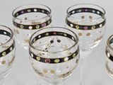 four wine glasses with gold and black designs on them on a white surface