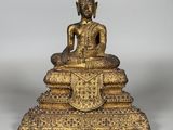 une statue en or représentant un Bouddha assis sur une pile de livres