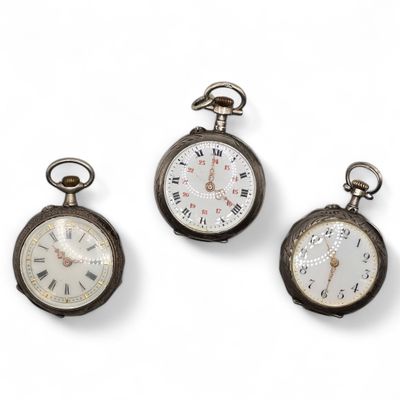 three antique pocket watches are displayed on a white surface