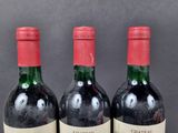 three bottles of red wine are lined up on a table