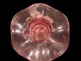 an image of a pink glass candle holder on a black background