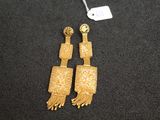 a pair of gold earrings with fringes on a black surface