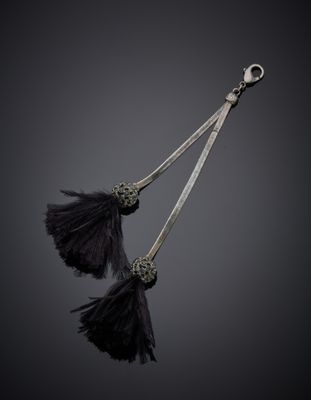 deux plumes noires sont suspendues à un crochet sur un fond noir