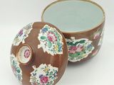 a brown bowl with a lid that has flowers on it
