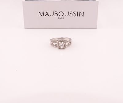 un gros plan d'une bague en diamant dans un écrin posé sur une surface blanche