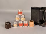 a small camera and several cans of paint next to each other