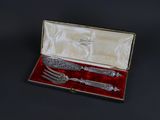 silverware in a box with a red velvet lining on a black surface