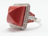 gros plan d'une bague avec une pierre rouge entourée de diamants