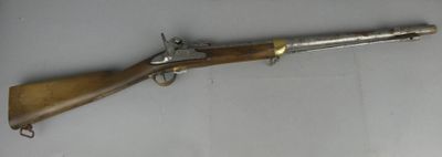 un vieux fusil au canon en bois et aux garnitures en laiton, posé sur une surface blanche