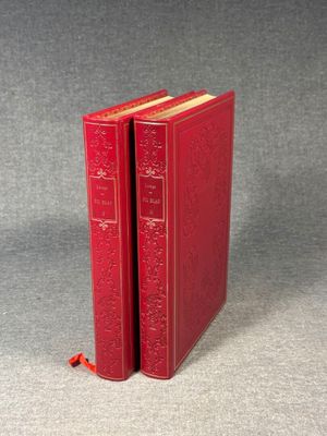 two red books sitting on top of each other on a gray surface
