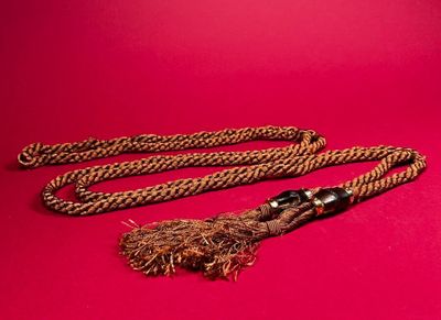 a close up of a rope with a tassel on a red background