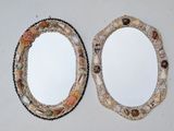two oval mirrors with shells on them on a table