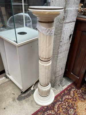 un socle blanc surmonté d'un bain d'oiseaux, placé devant une vitrine