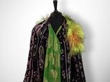 a black and green coat with a green scarf and a pink flower