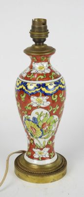 un vase rouge avec un socle doré sur fond blanc