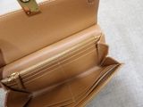 someone is holding a tan purse with a gold handle
