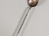 a silver spoon with a long handle on a white surface
