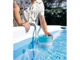Cet homme nettoie sa piscine avec un seau bleu.
