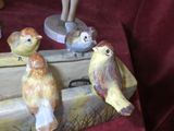 several figurines of birds sitting on top of a piece of wood