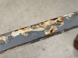 a close up of a rusted metal bar on a bench