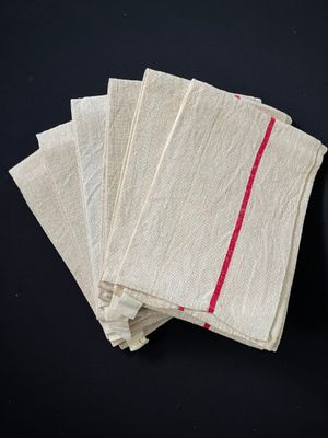 quatre serviettes blanches à rayures rouges posées sur une surface noire