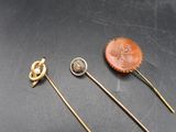 three gold pins and a broochle on a black surface