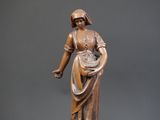 bronze statue of a woman with a hat and dress on a pedestal