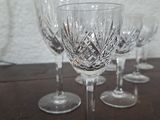 four wine glasses sitting on a table with a white wall in the background