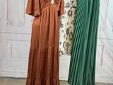 three dresses on a mannequin stand in front of a white wall
