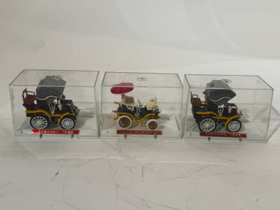 trois petites voitures dans une boîte transparente posée sur une surface blanche