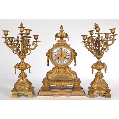 a gold clock and three candelabs on a white background