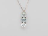 a three stone pendant with a chain on a white background