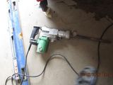 an image of a drill on the ground next to a piece of wood