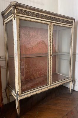 an antique display cabinet with glass doors in a room