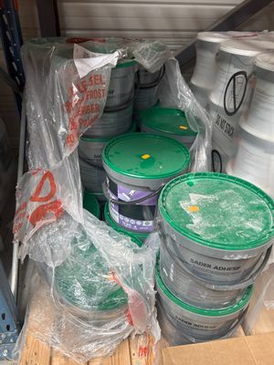 de nombreux seaux de peinture posés sur une palette dans un entrepôt