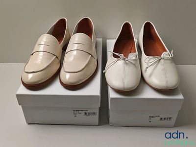 deux paires de chaussures blanches posées sur des cartons, sur une table