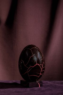 une boule de marbre noire posée sur un tissu violet