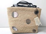 un sac en paille muni d'une étiquette, posé sur une table