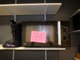 a microwave on a shelf with a post it note attached to it