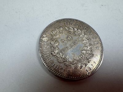 an old silver coin sitting on top of a white surface