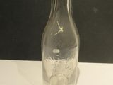 a clear glass bottle with a black lid on a white table