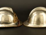 pair of silver plated hard hats on a black background