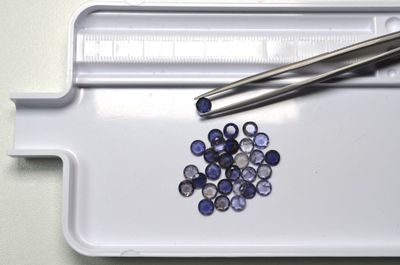un plateau blanc sur lequel se trouvent une paire de ciseaux et quelques pierres bleues