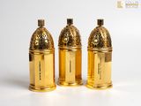 three golden bottles of perfume sitting on top of a white surface