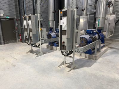 Plusieurs machines sont alignées dans une grande pièce dont l'un des murs…