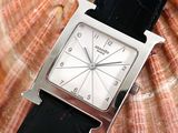 a close up of a watch with a shell in the background