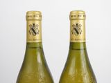 two bottles of white wine sitting next to each other on top of a table